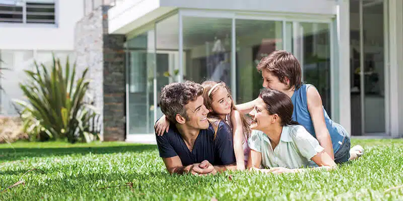 Une famille dans le jardin devant une maison individuelle moderne